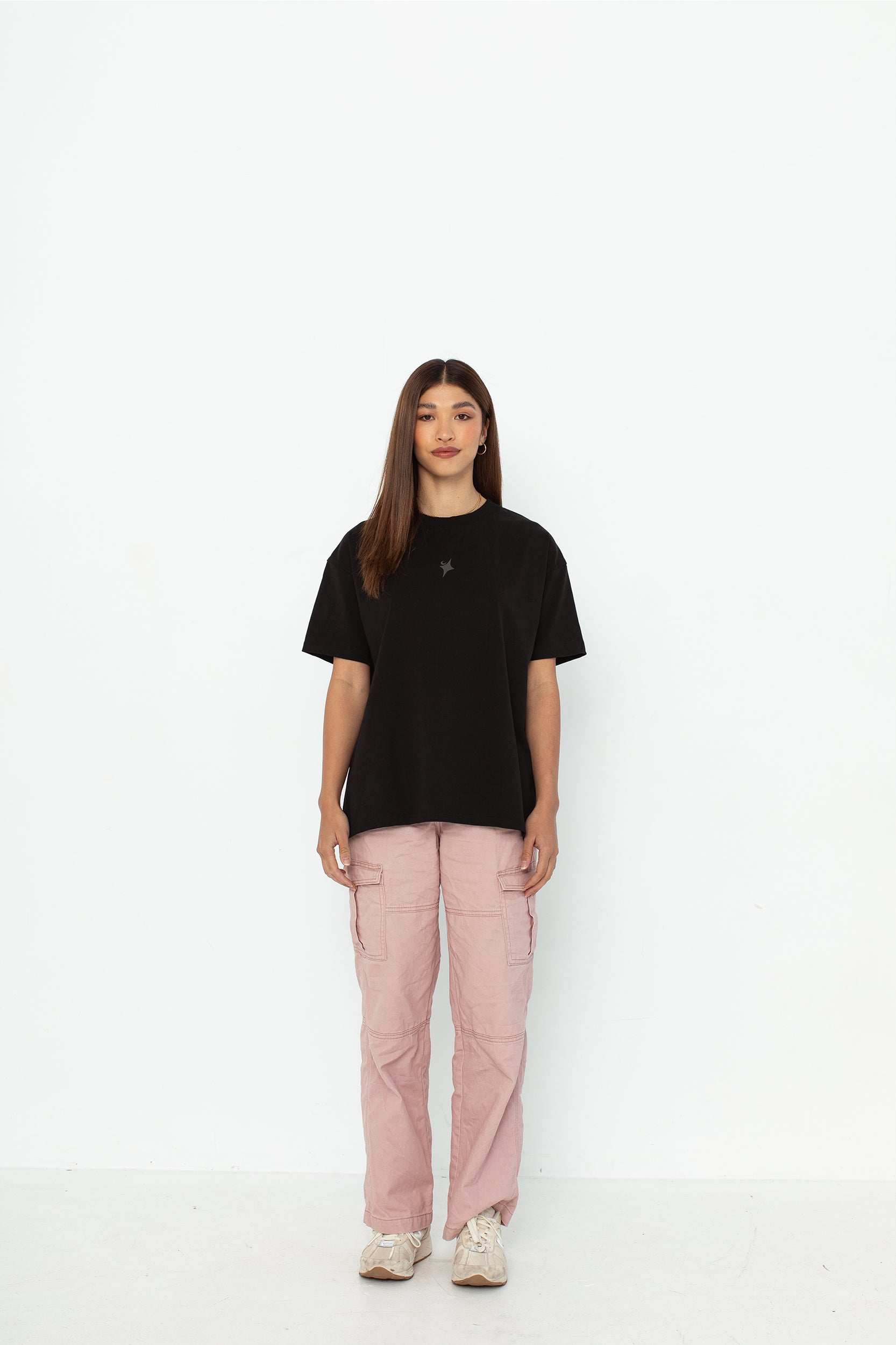 A model wearing a black oversized kohz  t-shirt with a puff printed logo, crew neck, and short sleeves standing against a white background.
