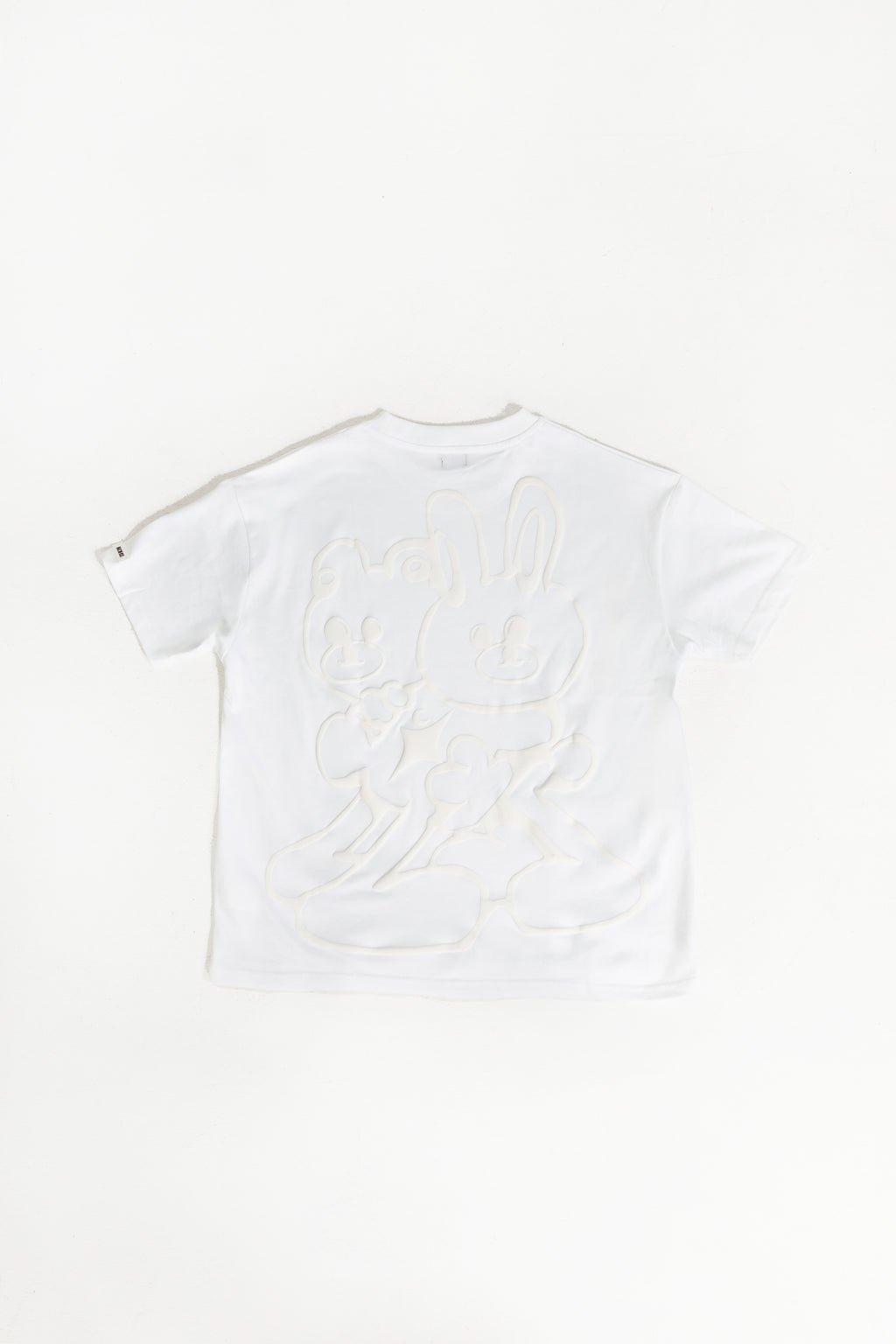 back of white oversized crewneck t-shirt with ribbed sleeves and a puff printed logo on the chest.
