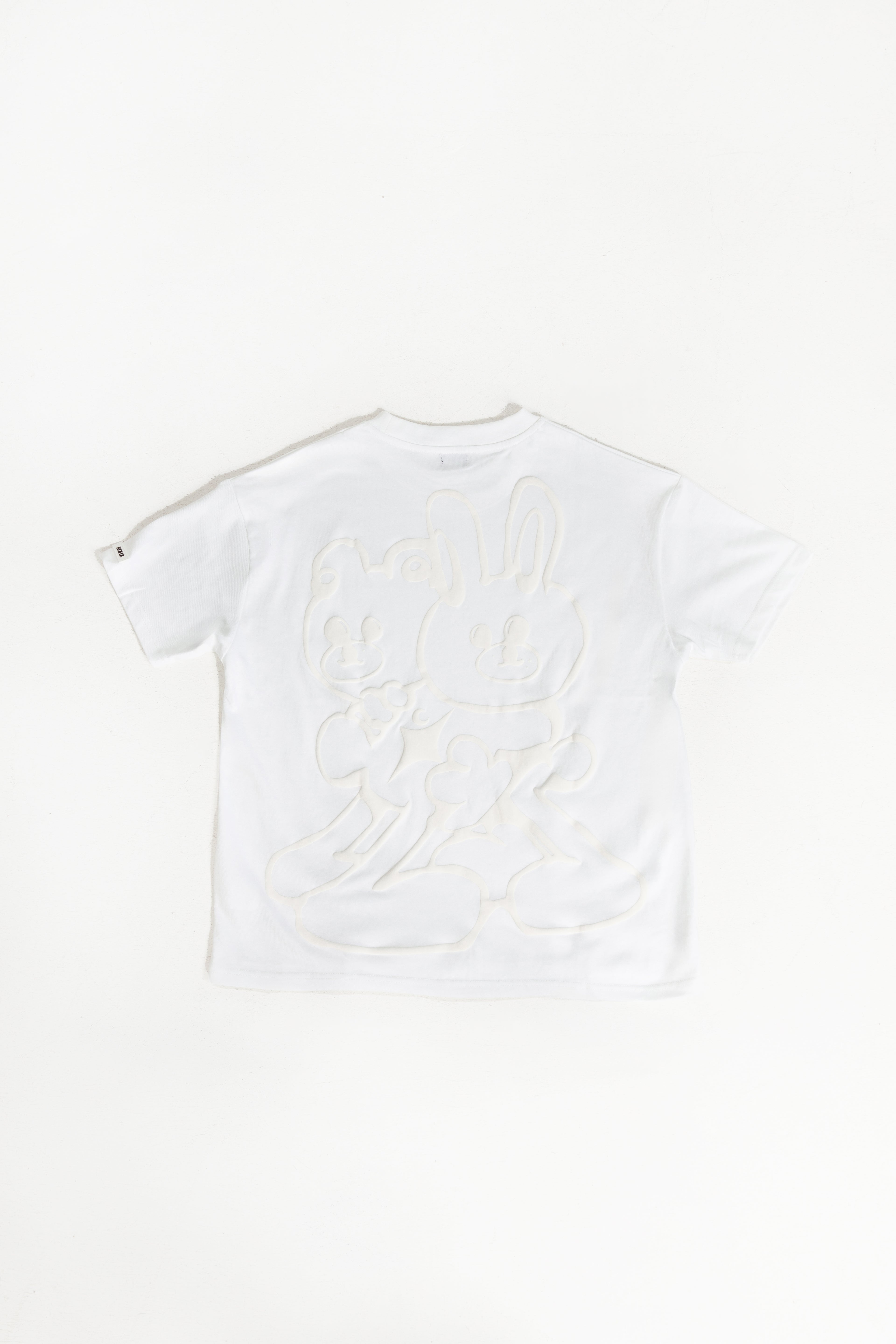 back of white oversized crewneck t-shirt with ribbed sleeves and a puff printed logo on the chest.