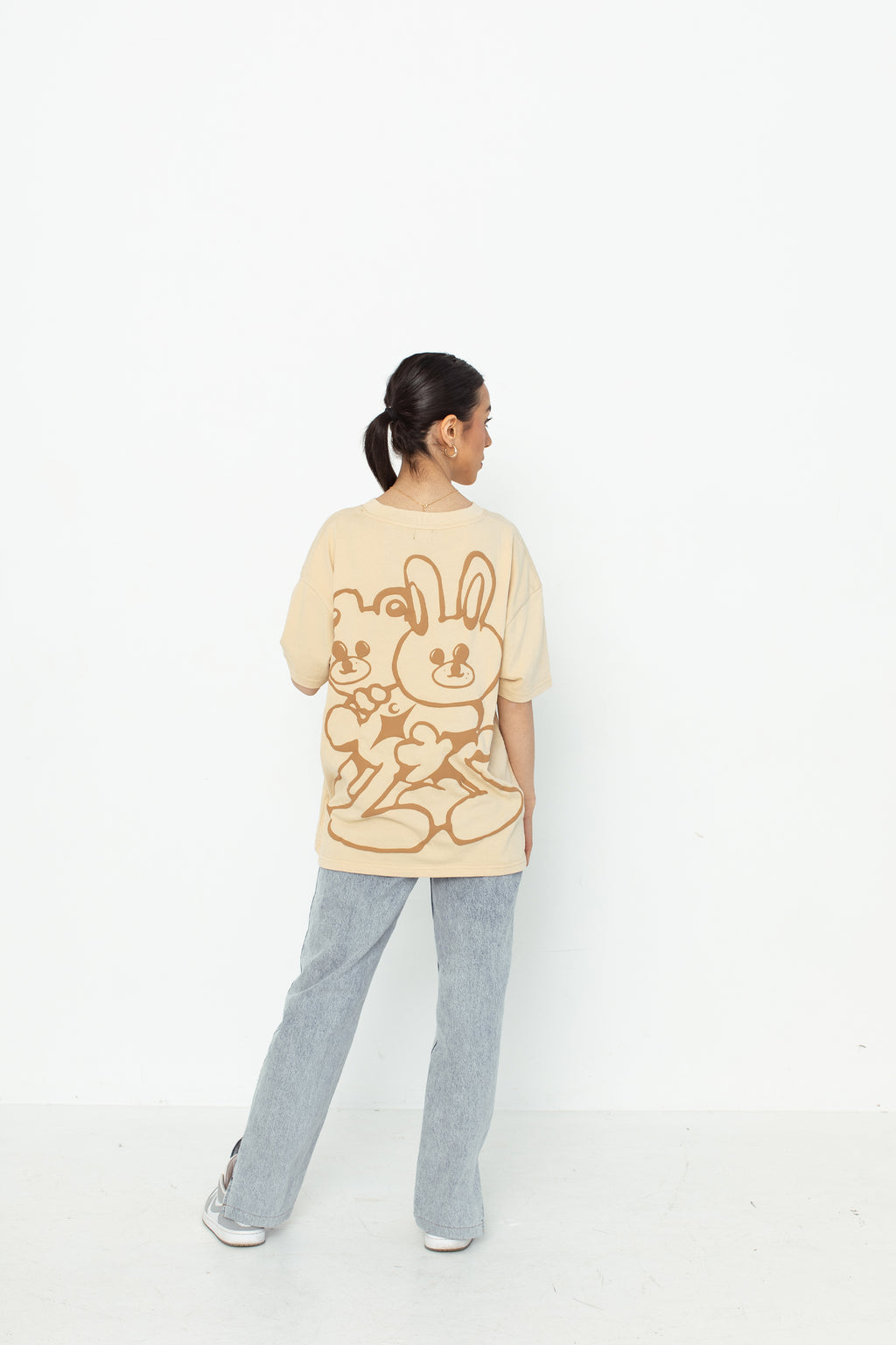 A model wearing a white oversized kohz bb t-shirt with a puff printed logo, crew neck, and short sleeves standing against a white background.