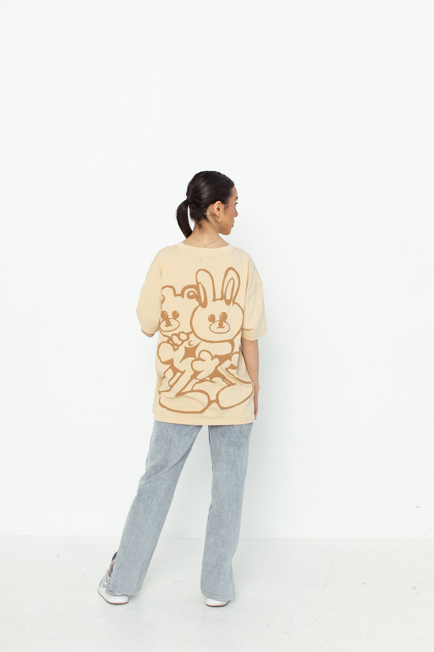 A model wearing a white oversized kohz bb t-shirt with a puff printed logo, crew neck, and short sleeves standing against a white background.