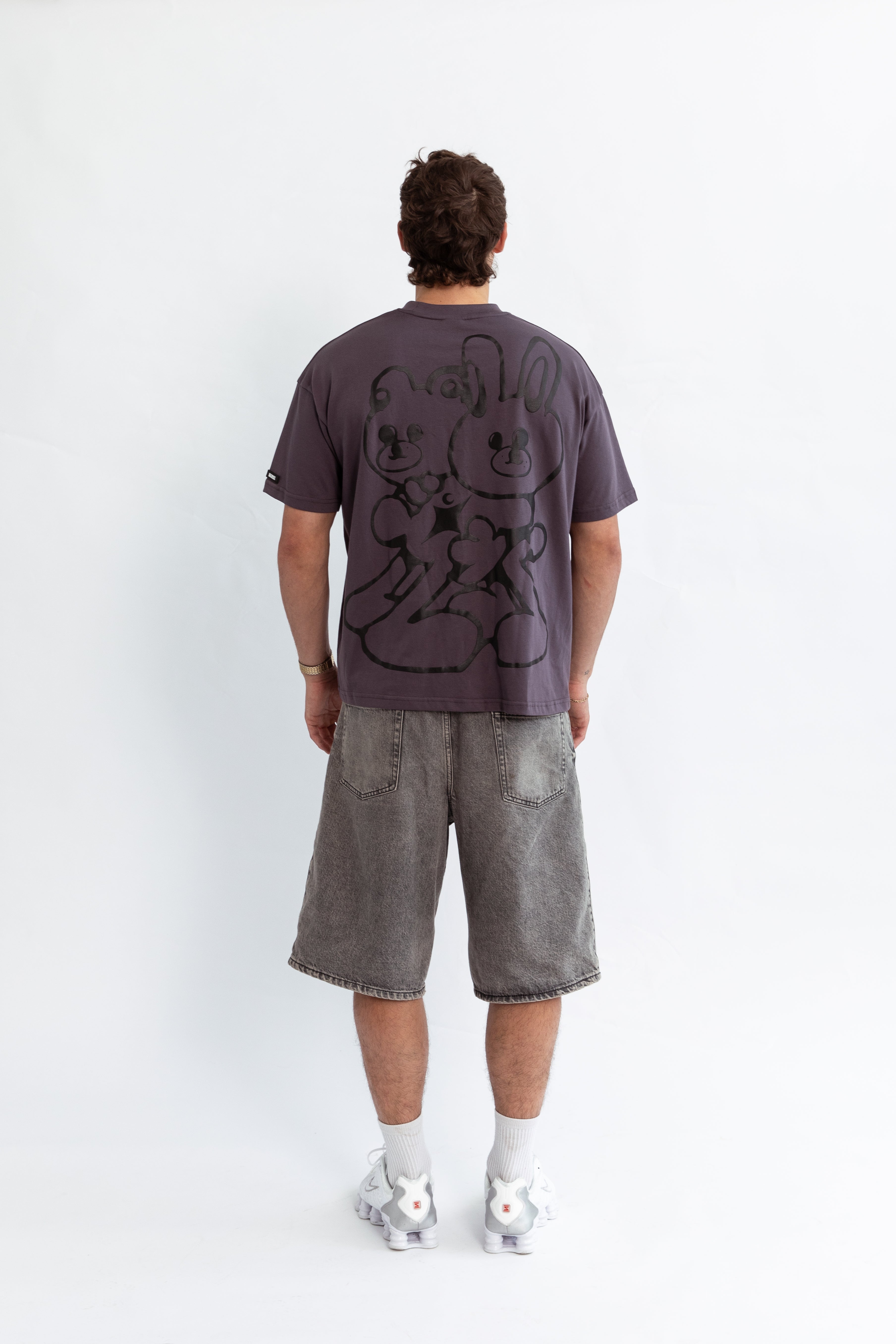 A model wearing a grey oversized kohz bb t-shirt with a puff printed logo, crew neck, and short sleeves standing against a white background.