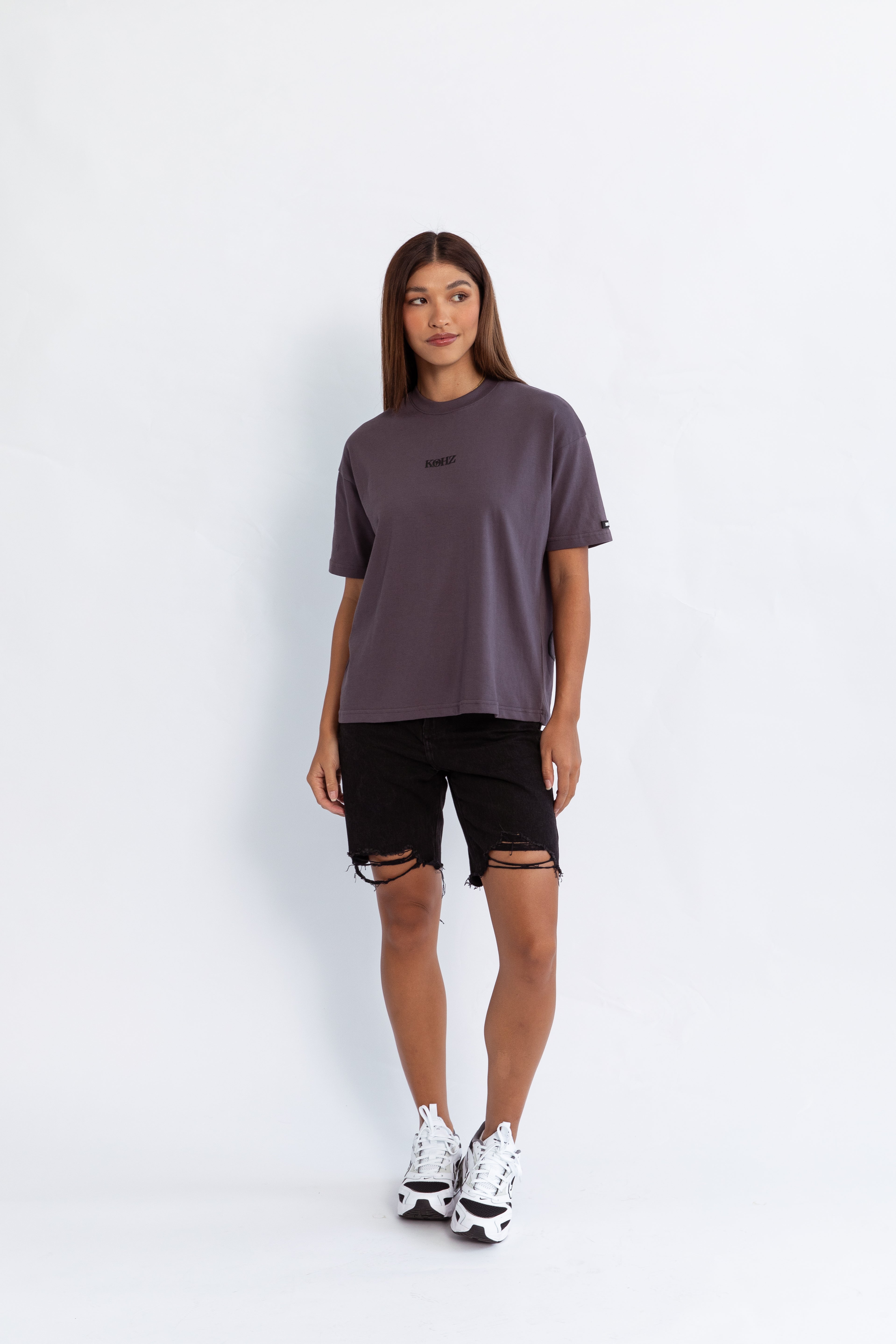 A model wearing a grey oversized kohz bb t-shirt with a puff printed logo, crew neck, and short sleeves standing against a white background.