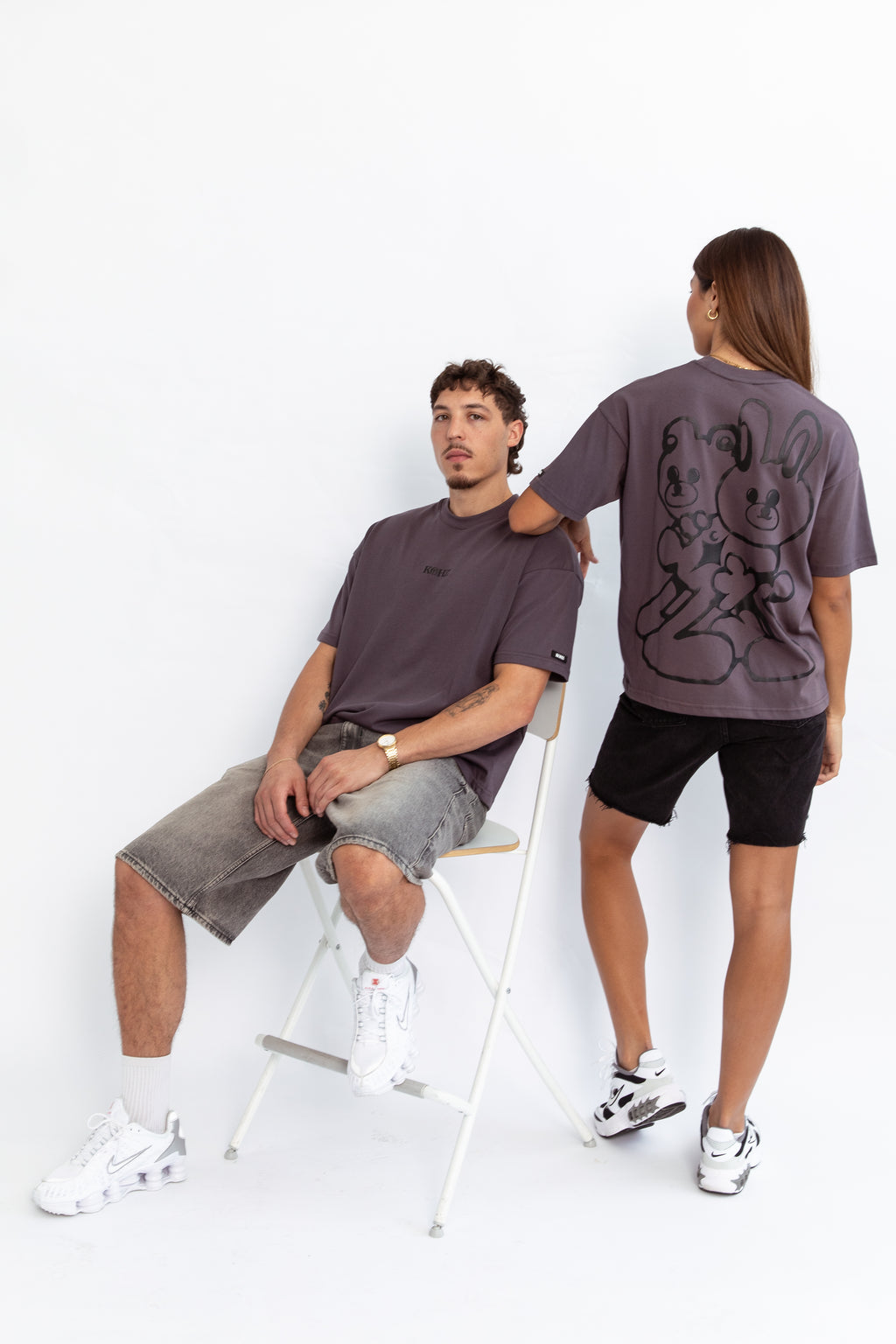 two models wearing a grey oversized kohz bb t-shirt with a puff printed logo, crew neck, and short sleeves standing against a white background.