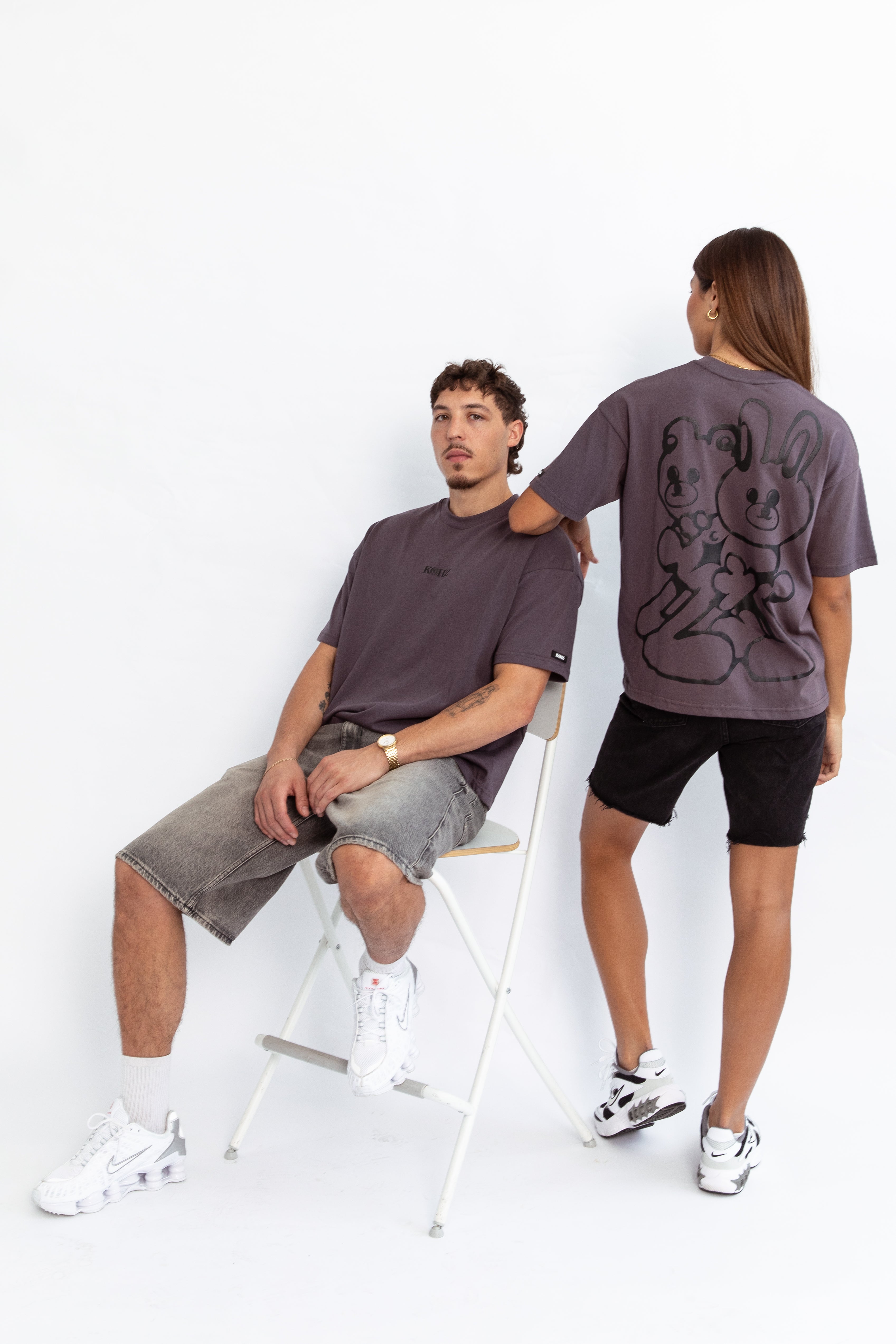 two models wearing a grey oversized kohz bb t-shirt with a puff printed logo, crew neck, and short sleeves standing against a white background.