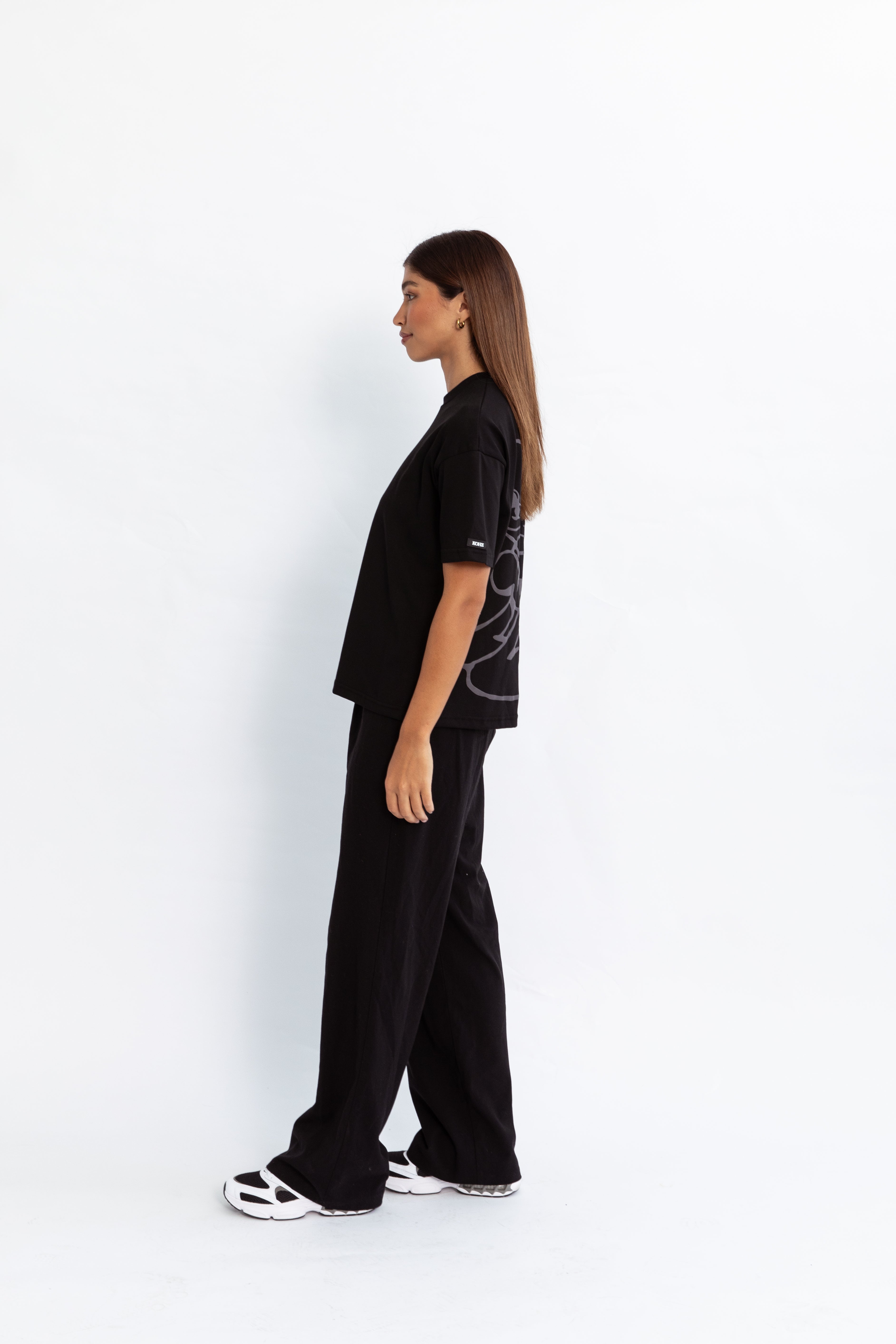 A model wearing a black oversized kohz bb t-shirt with a puff printed logo, crew neck, and short sleeves standing against a white background.