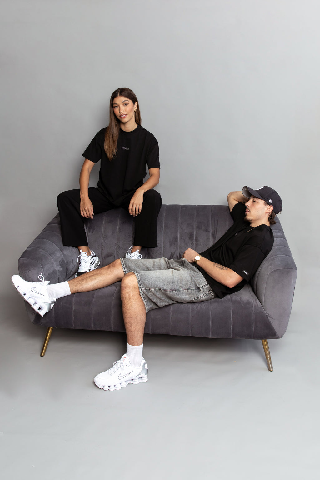 A model wearing a black oversized kohz bb t-shirt with a puff printed logo, crew neck, and short sleeves standing against a grey background.