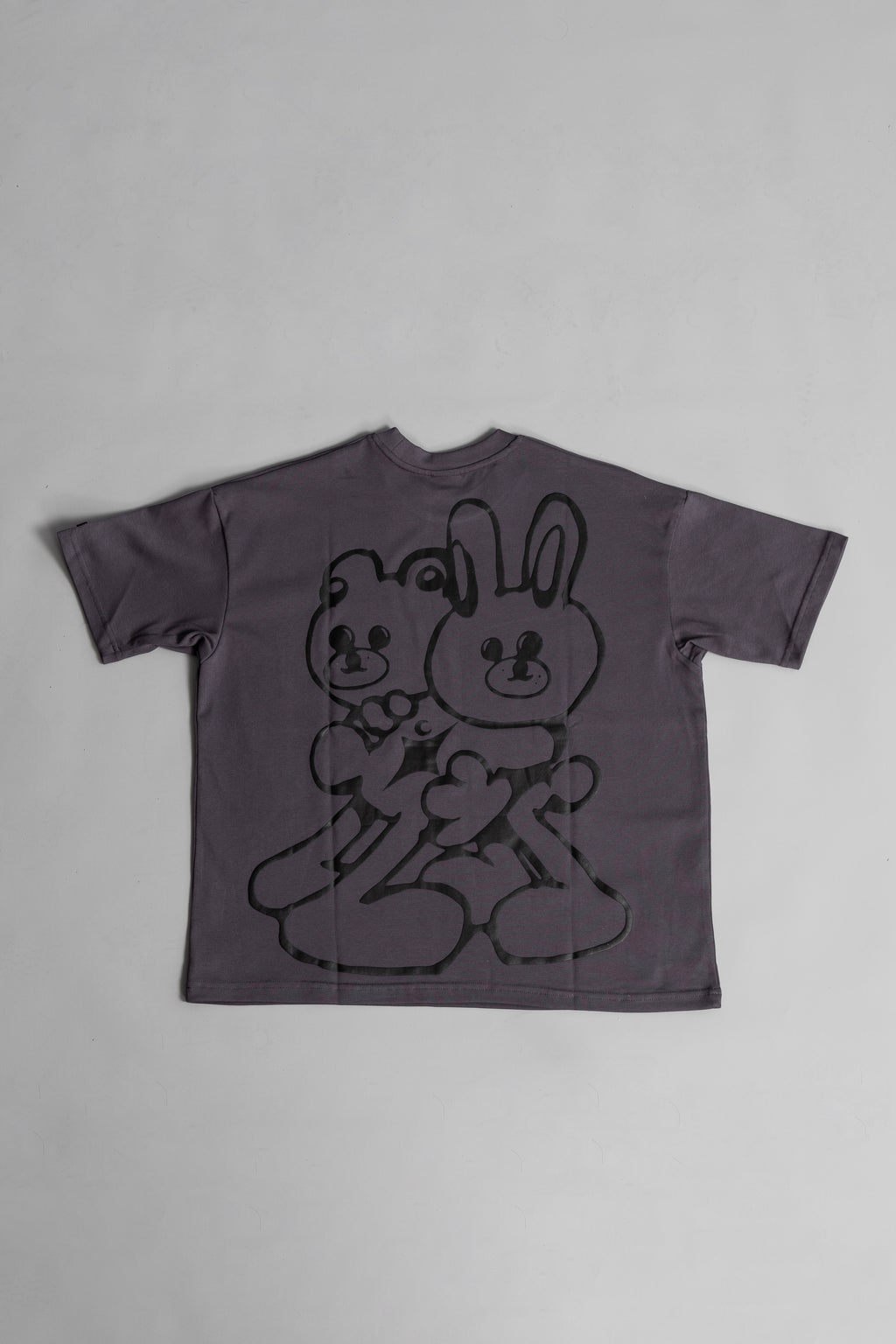 Back of grey oversized crewneck t-shirt with ribbed sleeves and a puff printed logo on the chest.