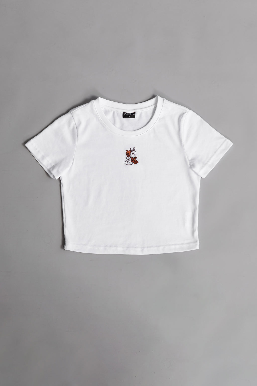 A white crewneck kohz bb crop t-shirt with embroidery on the chest.