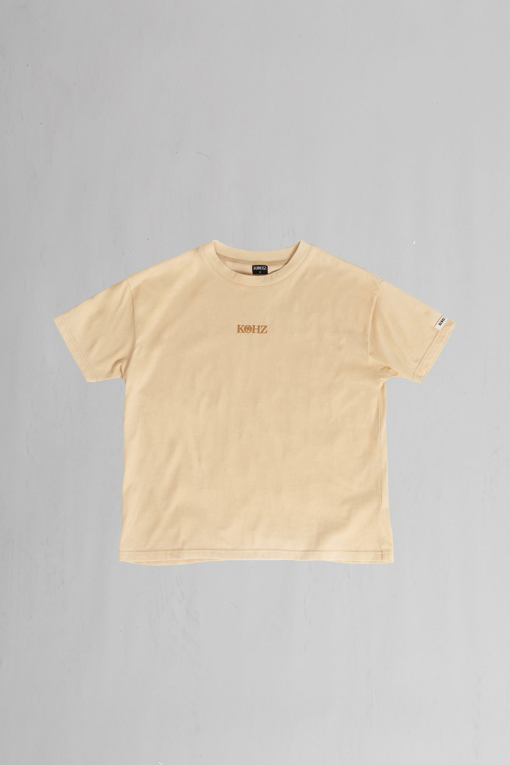 front of beige oversized crewneck t-shirt with ribbed sleeves and a puff printed logo on the chest.