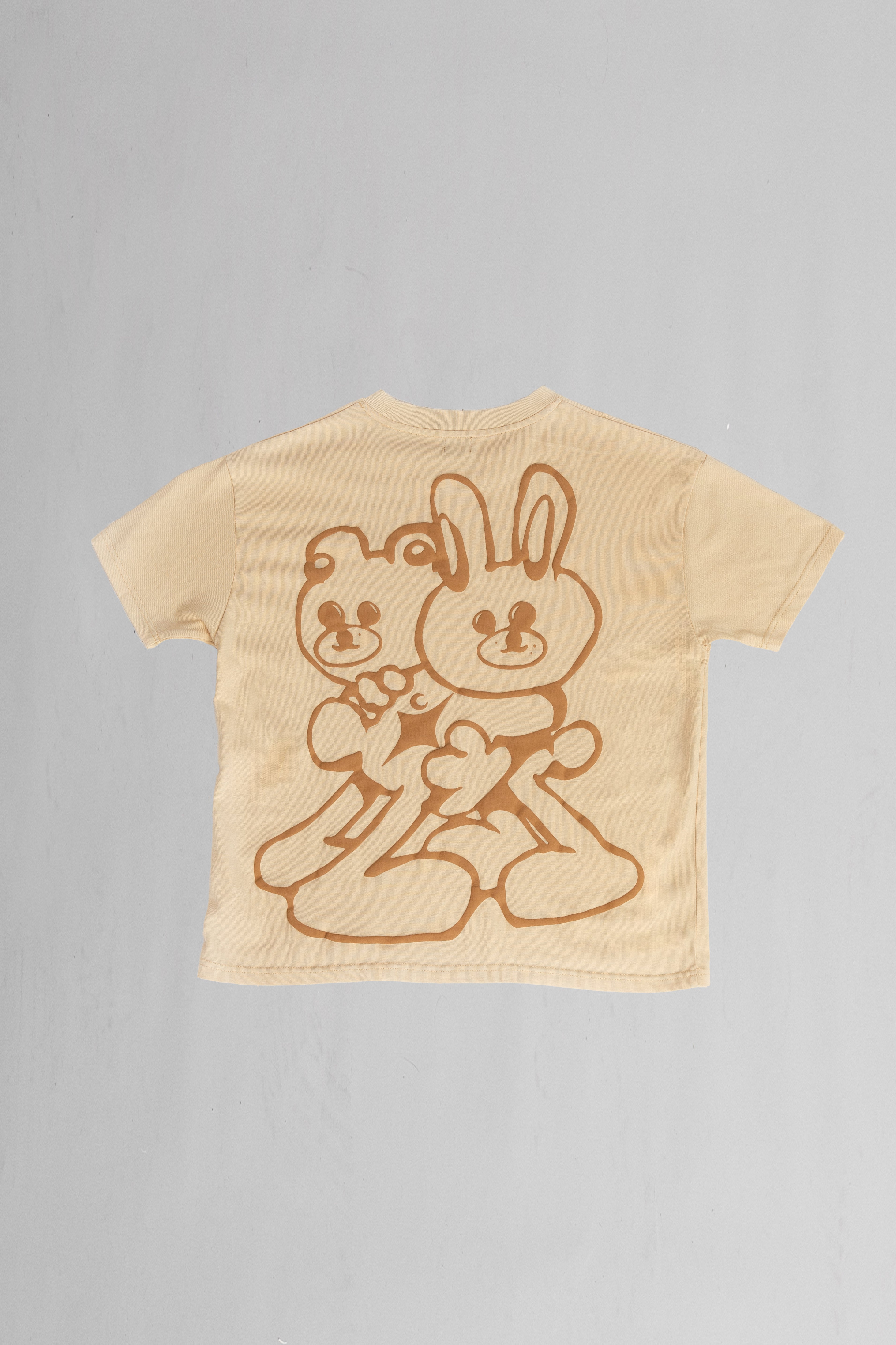 Back of beige oversized crewneck t-shirt with ribbed sleeves and a puff printed logo on the chest.