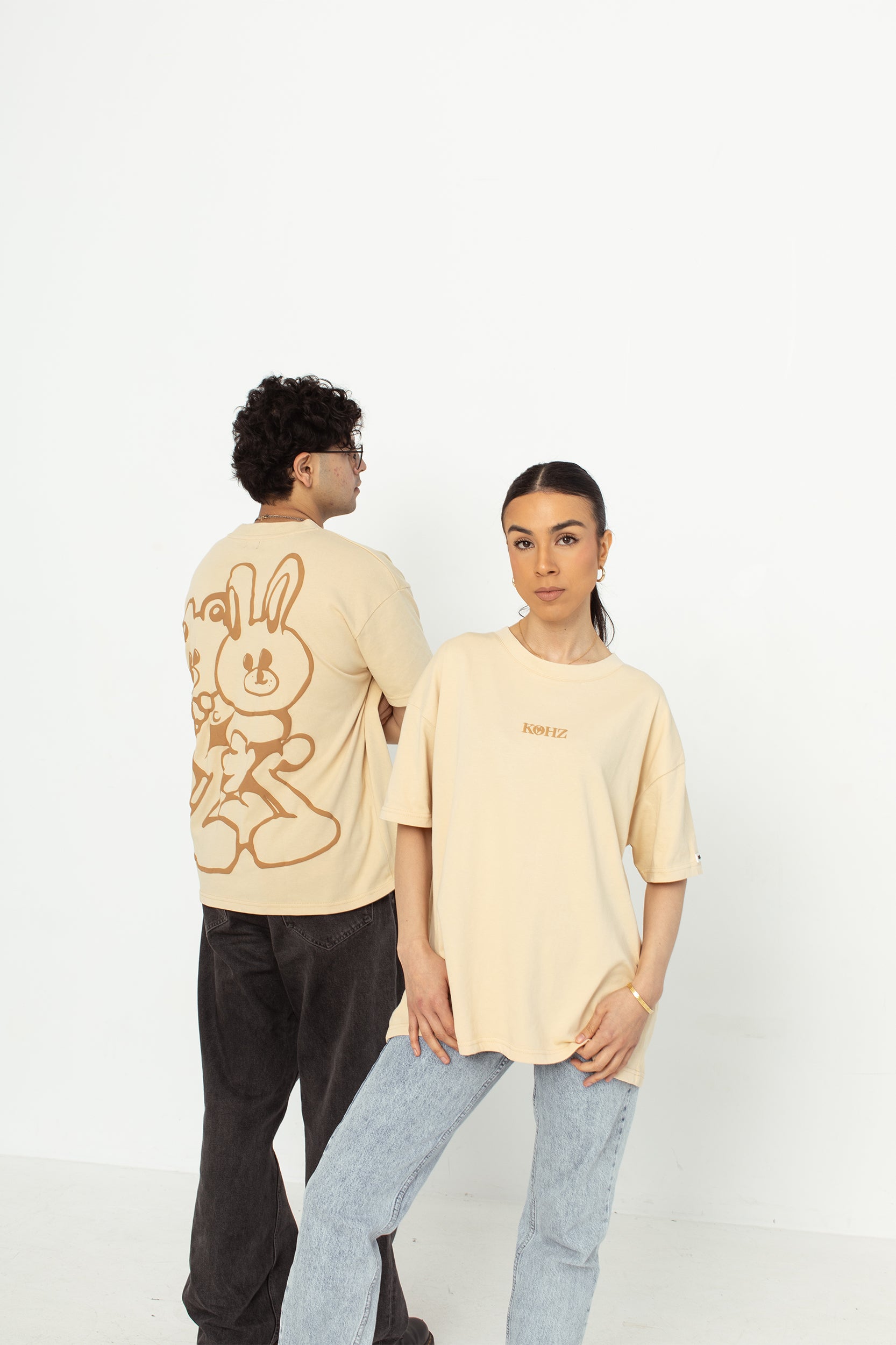 two models wearing a white oversized kohz bb t-shirt with a puff printed logo, crew neck, and short sleeves standing against a white background.